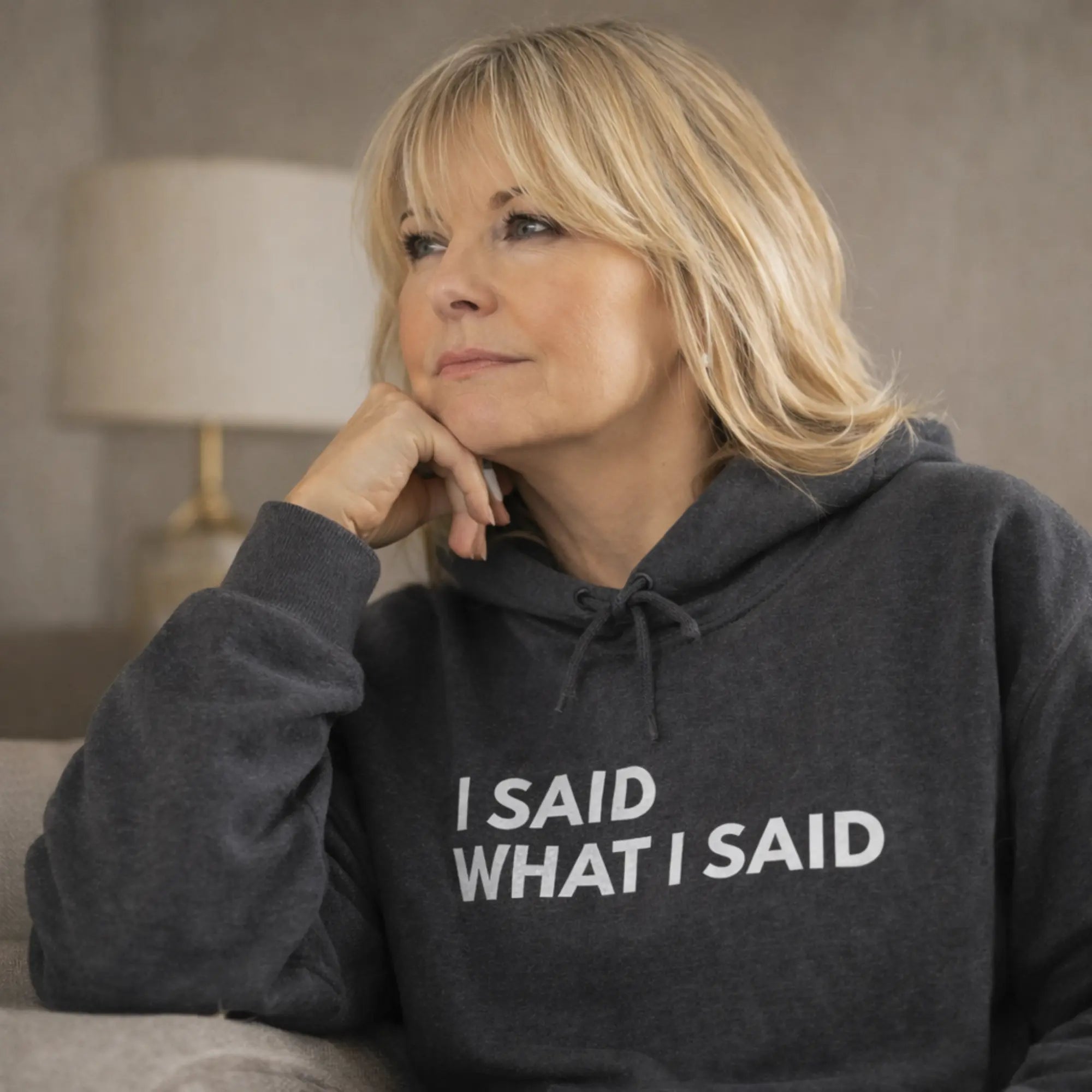 dark heather “I said what I said” hoodie worn by UK woman sitting on sofa