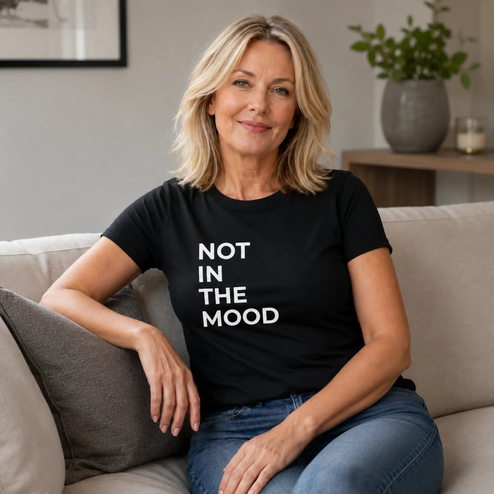 Woman wearing Not In The Mood black slogan tee with jeans at home