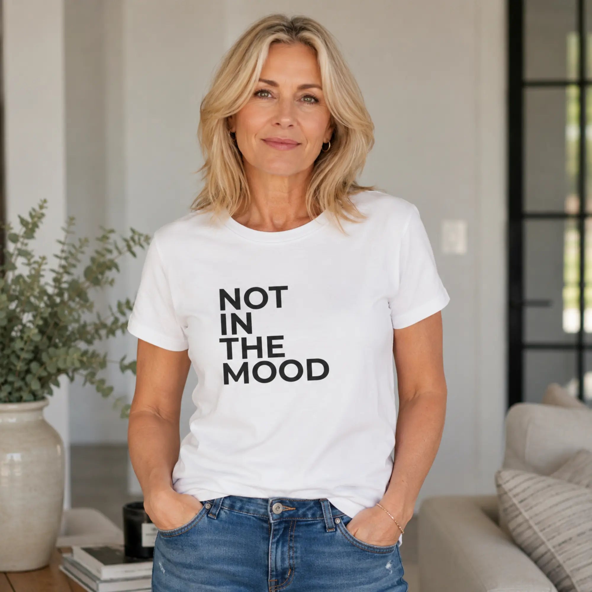 Woman wearing Not In The Mood white slogan tee with jeans at home