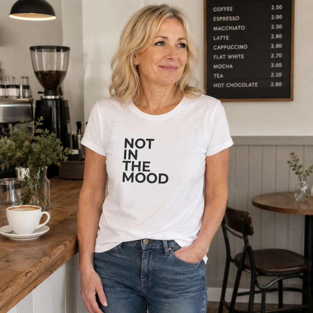 Woman wearing Not In The Mood white slogan t-shirt in a stylish café