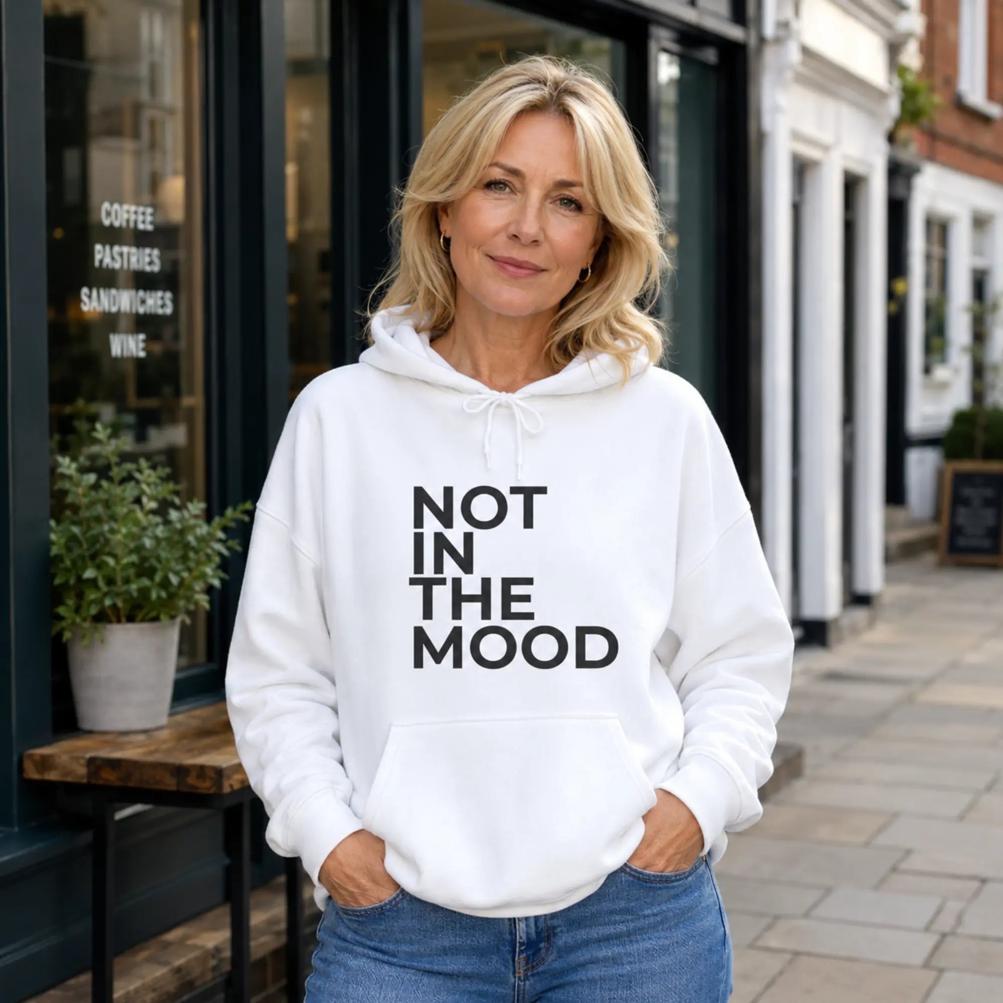 Woman wearing Not In The Mood white slogan hoodie on a British high street